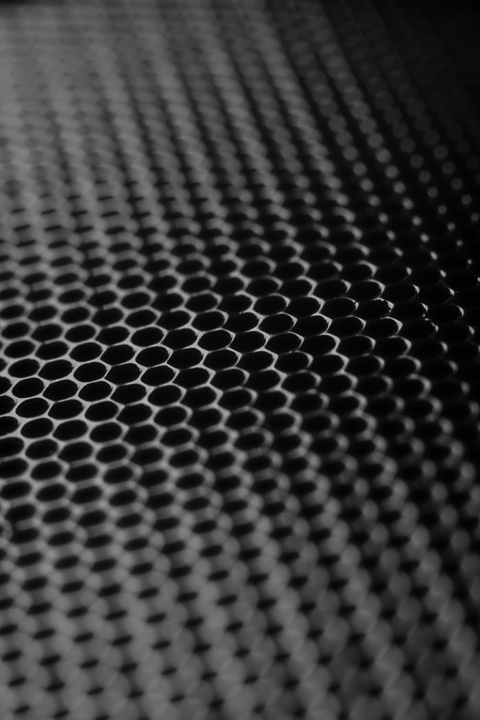 Abstract close-up of a metallic honeycomb grid with a monochromatic tone.